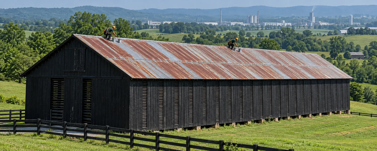Long black barn with rusty metal roof panels and laps that need sealing